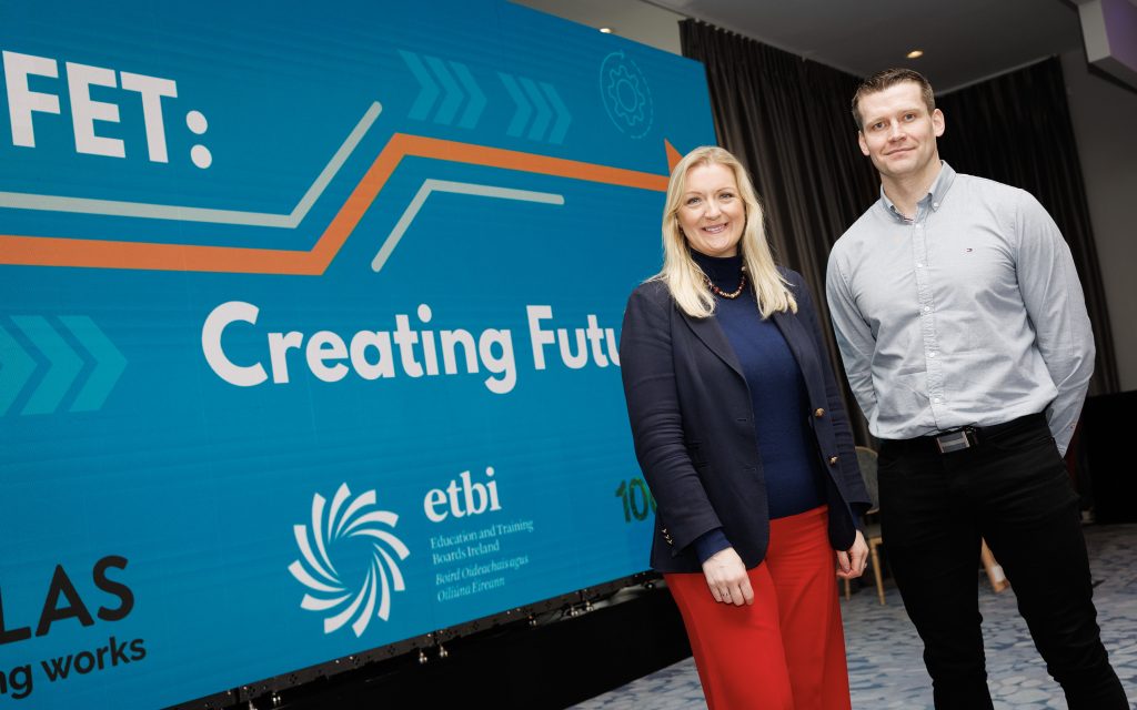 Man and woman posing in front of large screen