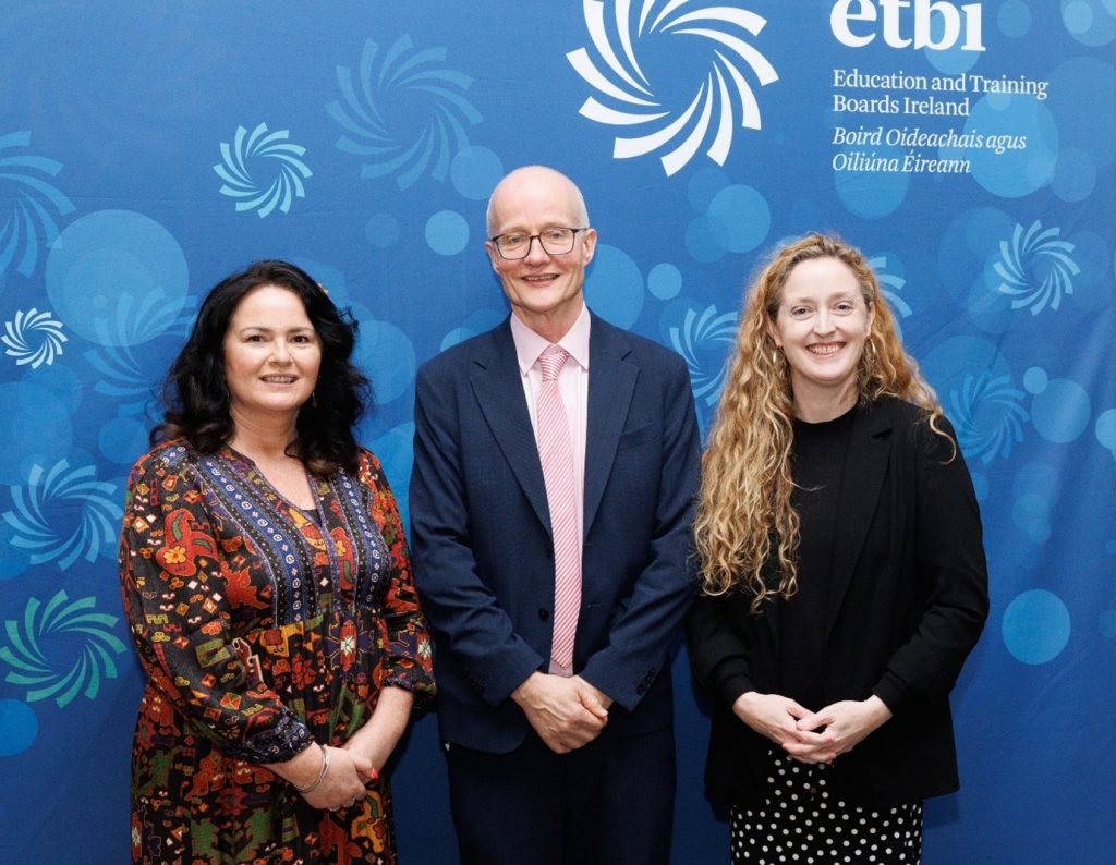 Two woman stood on either side of a man