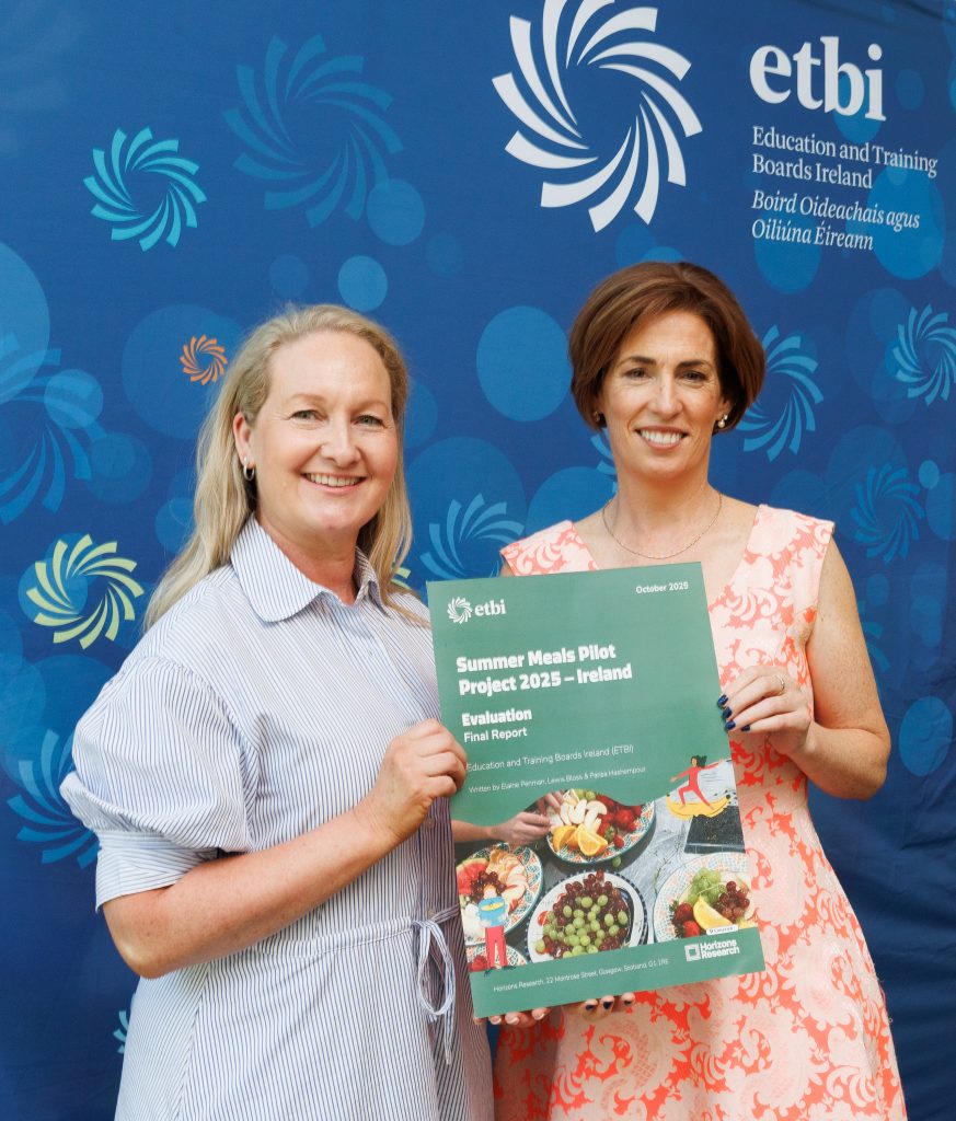Two ladies posing with a poster that says Summer Meals pilot project report